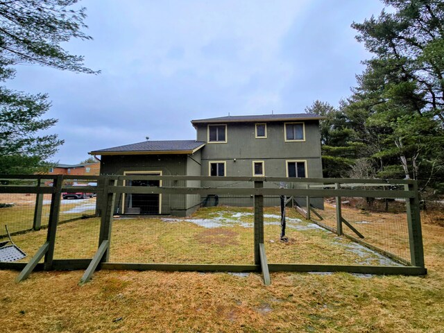 back of property with a lawn and fence