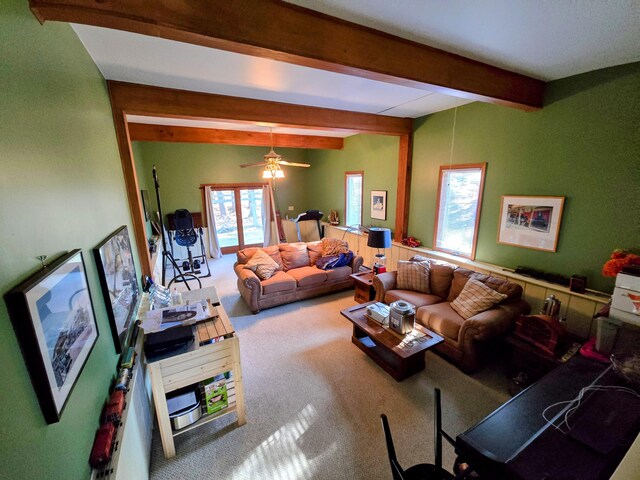 carpeted living area with beamed ceiling