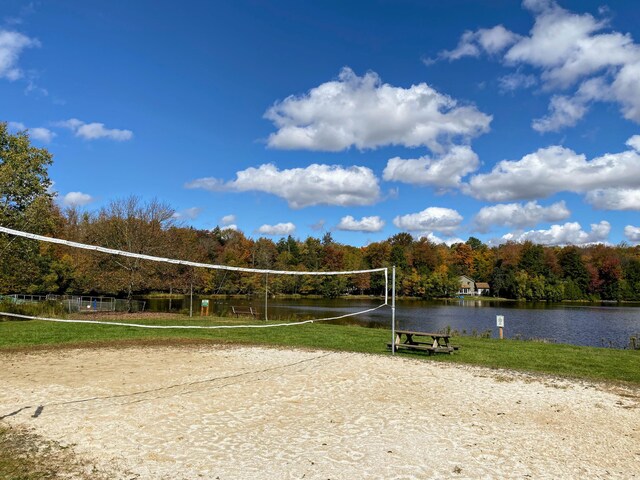 surrounding community with a water view, a view of trees, and volleyball court