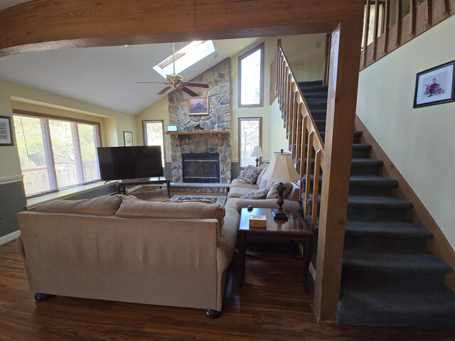 living room with dark wood-type flooring, a skylight, a stone fireplace, and stairs