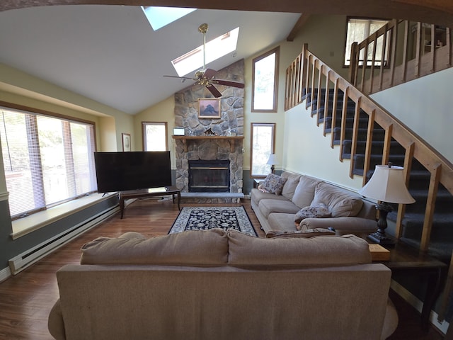 living room featuring a stone fireplace, a baseboard radiator, a skylight, wood finished floors, and stairs