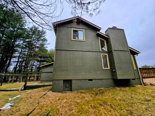 view of property exterior with crawl space, a chimney, and a lawn