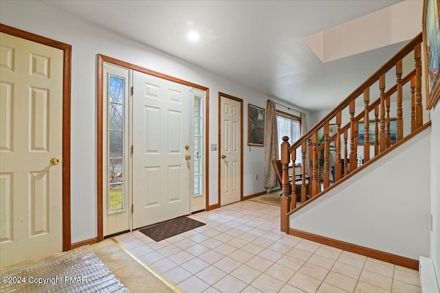 foyer entrance featuring stairs, light tile patterned floors, and baseboards