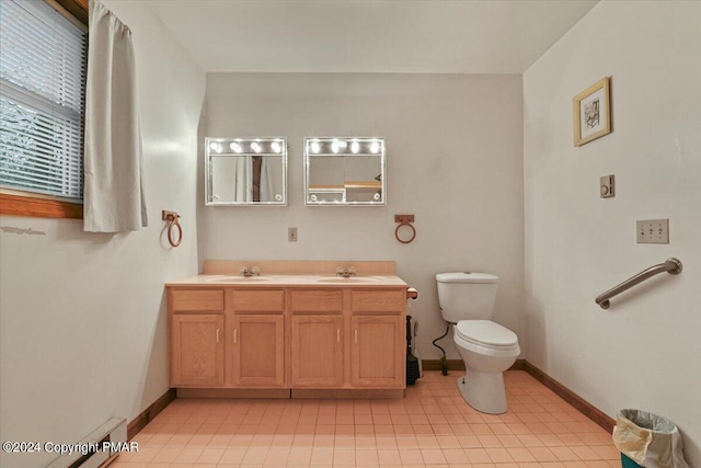 bathroom with baseboards, a sink, toilet, and double vanity