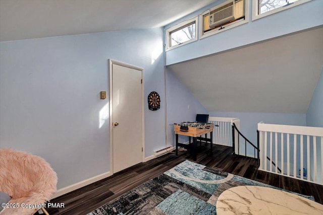 interior space with dark hardwood / wood-style flooring, a baseboard heating unit, vaulted ceiling, and an AC wall unit