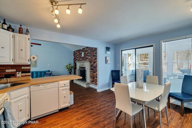 dining area featuring sink, dark wood-type flooring, and a fireplace