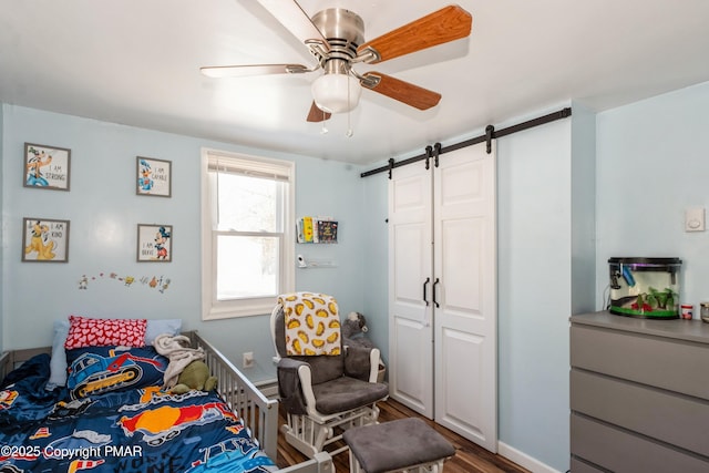 bedroom with a barn door, hardwood / wood-style floors, and ceiling fan