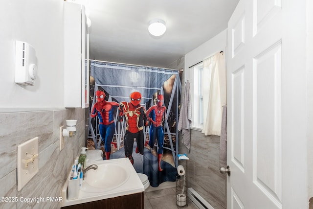 bathroom featuring curtained shower, tile walls, tile patterned flooring, vanity, and baseboard heating