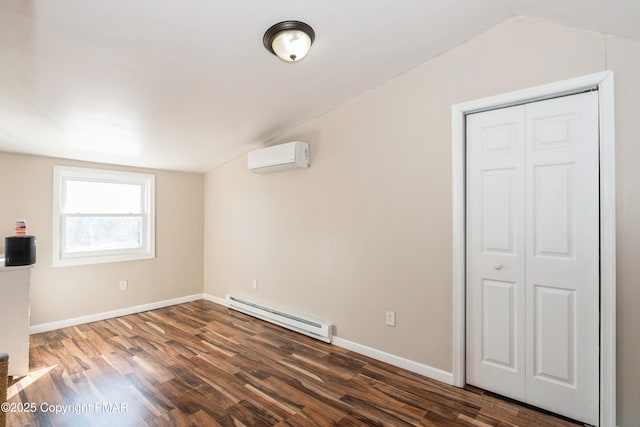 spare room featuring baseboard heating, a wall mounted air conditioner, vaulted ceiling, and dark wood-type flooring