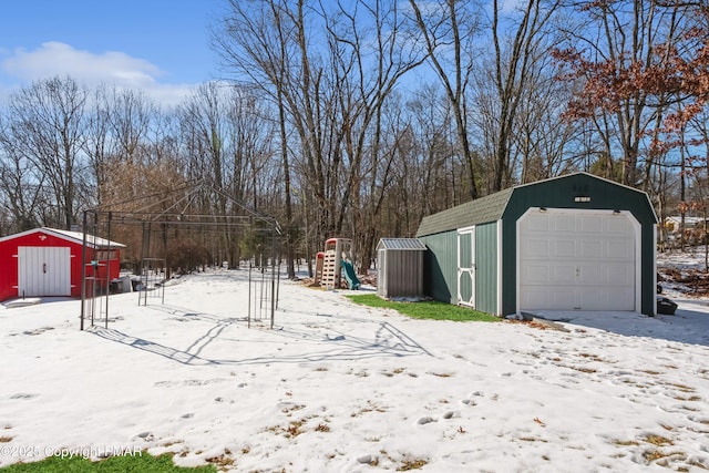 yard covered in snow featuring a garage, an outdoor structure, and a playground