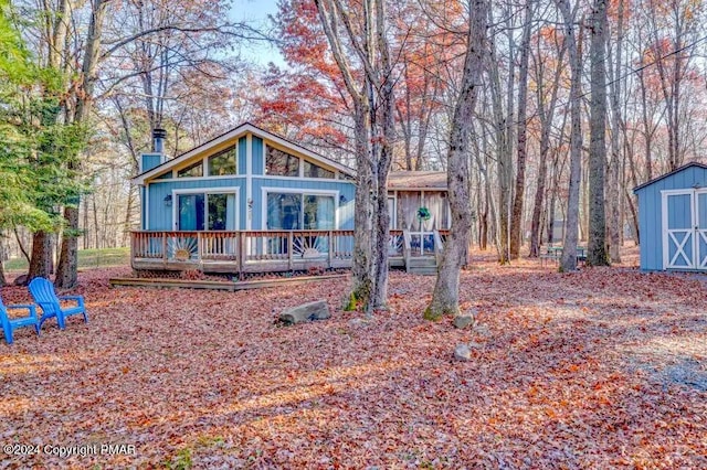 chalet / cabin with an outbuilding, a deck, and a storage shed