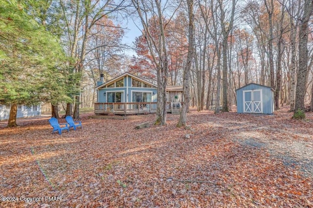 exterior space featuring a shed, a chimney, a deck, and an outdoor structure