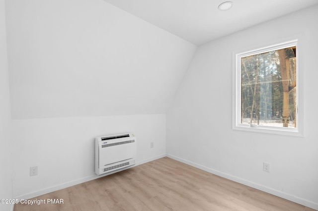 bonus room with light wood-style floors, baseboards, vaulted ceiling, and heating unit