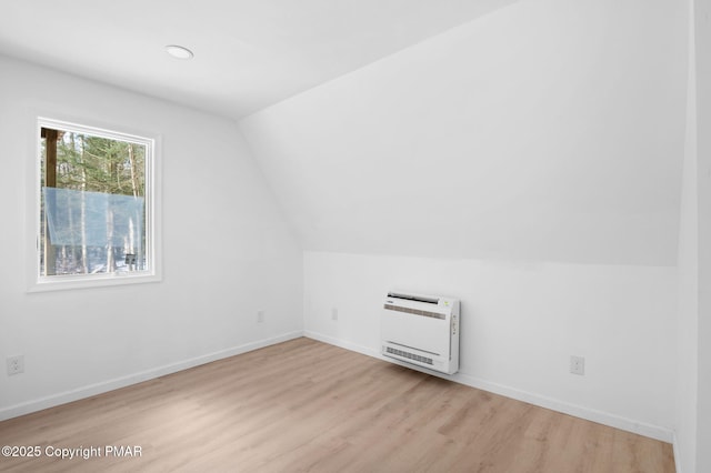 additional living space featuring vaulted ceiling, baseboards, wood finished floors, and heating unit