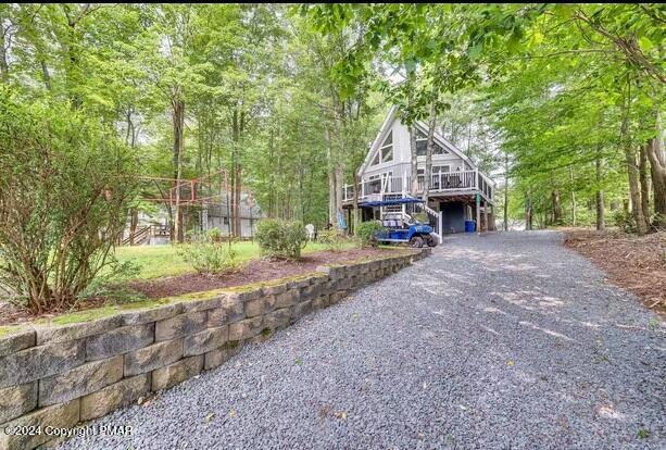 chalet / cabin featuring stairway, gravel driveway, and a deck