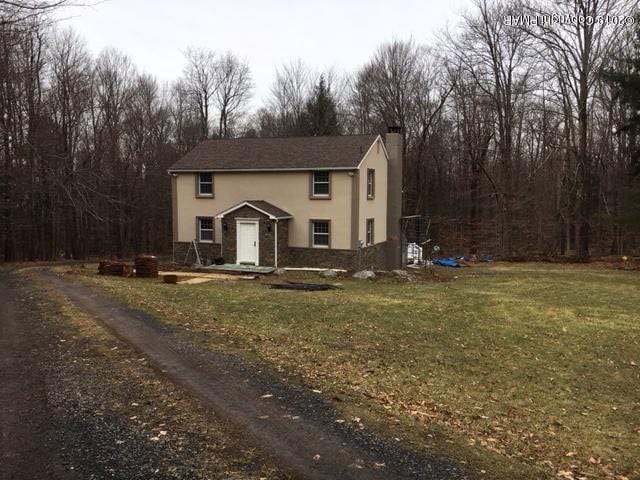 view of front of house featuring a chimney, a front yard, and stucco siding