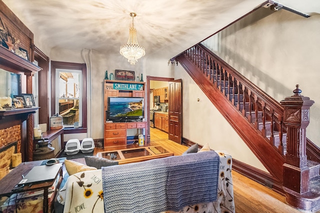 living room with stairway, baseboards, a notable chandelier, and wood finished floors