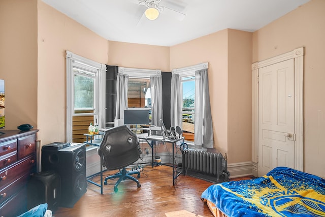 bedroom with ceiling fan, baseboards, hardwood / wood-style floors, and radiator heating unit