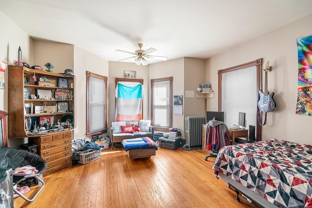 bedroom with hardwood / wood-style flooring, radiator, and ceiling fan