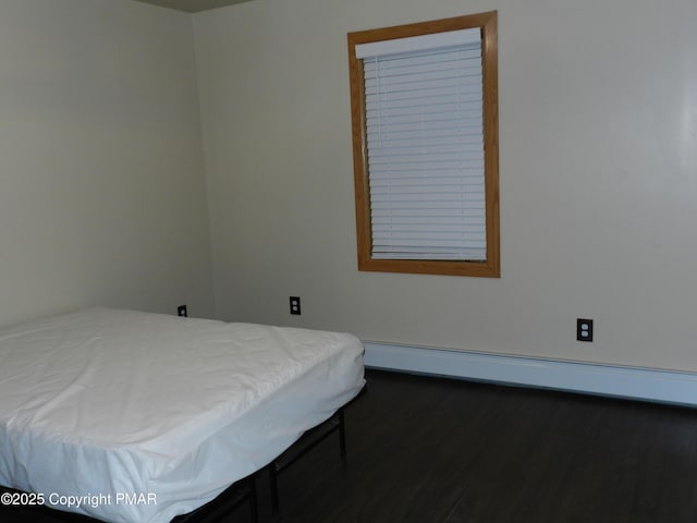 bedroom with a baseboard radiator and wood finished floors