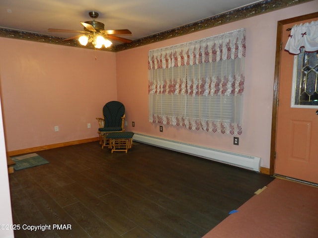 unfurnished room featuring a baseboard heating unit, ceiling fan, baseboards, and wood finished floors