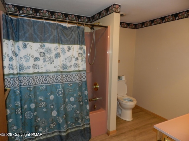 bathroom featuring shower / bath combo with shower curtain, baseboards, toilet, and wood finished floors