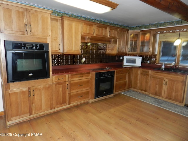 kitchen featuring light wood-style floors, black oven, ventilation hood, and white microwave