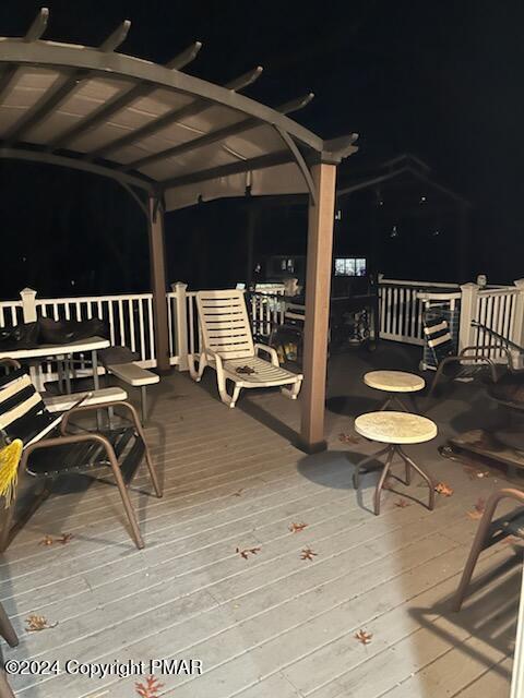 deck at night featuring a pergola