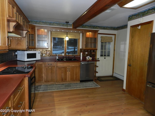 kitchen featuring exhaust hood, a sink, brown cabinets, black appliances, and light wood finished floors