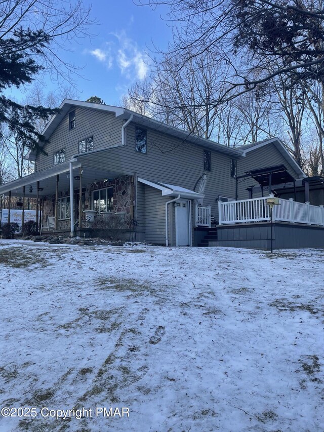 snow covered house with a garage and covered porch