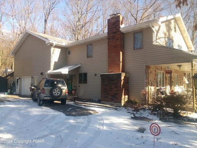 snow covered house featuring a garage