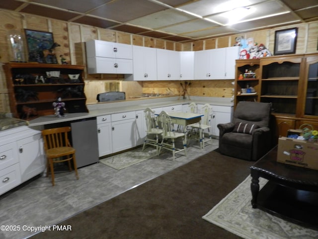 kitchen with refrigerator, light countertops, concrete floors, and white cabinets