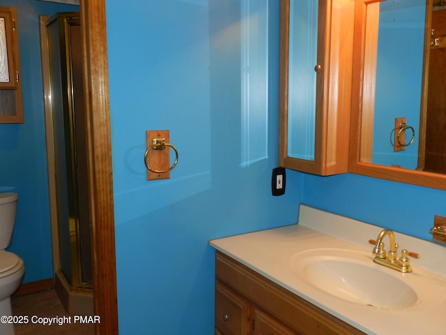 bathroom with vanity, a shower with shower door, and toilet