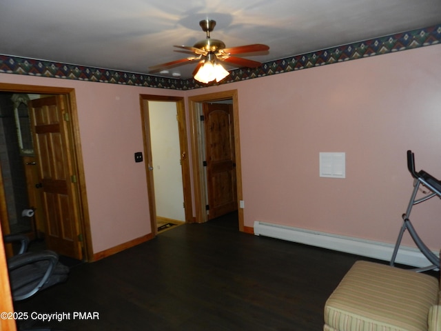 unfurnished room featuring ceiling fan, baseboard heating, wood finished floors, and baseboards