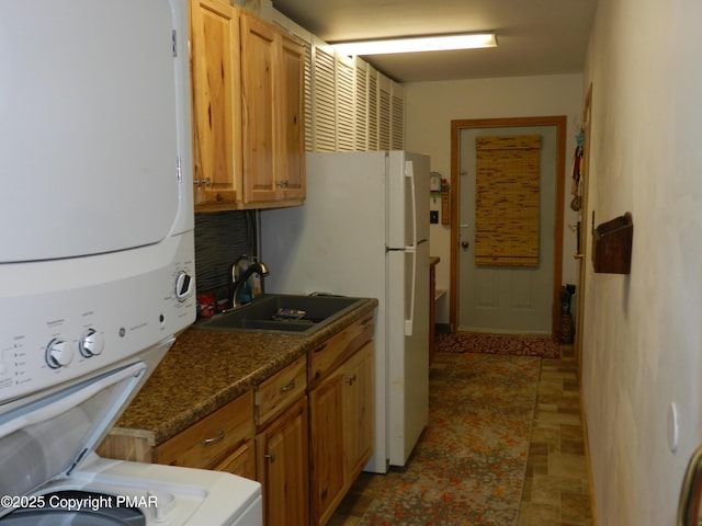 kitchen with brown cabinetry, stacked washing maching and dryer, and a sink