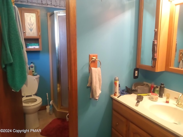 bathroom with toilet, a shower stall, and vanity