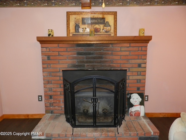 interior details with a brick fireplace, baseboards, and wood finished floors