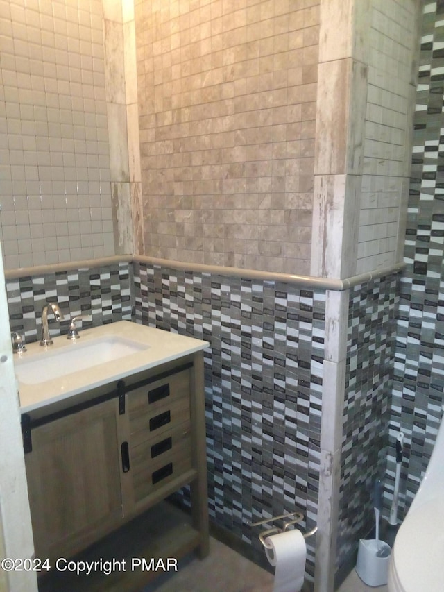 bathroom featuring vanity, toilet, and tile walls