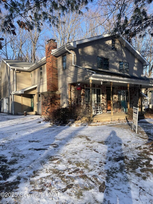 snow covered property featuring covered porch