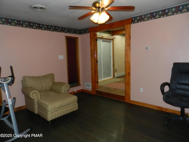 living area with wood finished floors, visible vents, baseboards, a ceiling fan, and baseboard heating