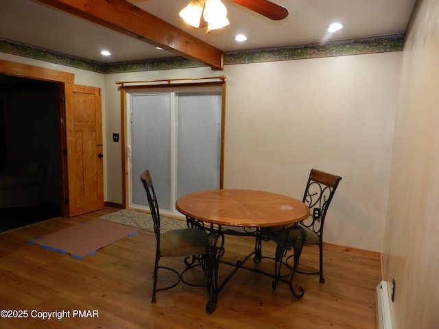 dining space featuring ceiling fan, beam ceiling, a baseboard radiator, and wood-type flooring