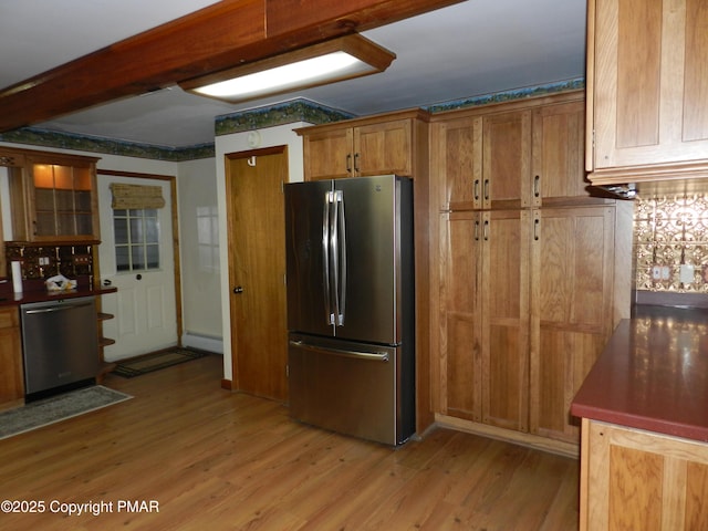 kitchen featuring stainless steel appliances, a baseboard heating unit, decorative backsplash, and light hardwood / wood-style flooring