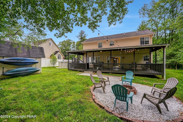 back of property with a fire pit, a yard, a deck, and fence