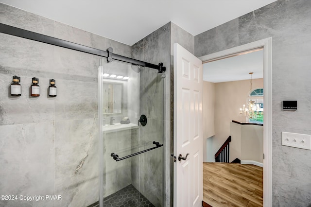 bathroom featuring a chandelier, a shower stall, and wood finished floors