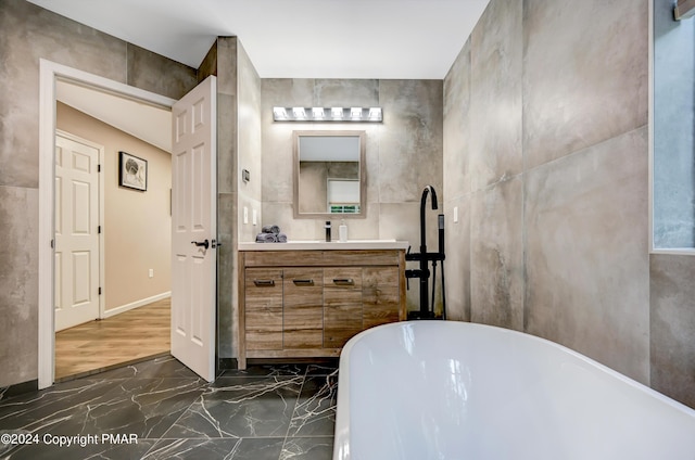 full bath featuring marble finish floor, a freestanding bath, and vanity