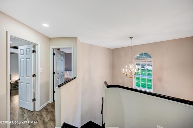 hall featuring a chandelier, recessed lighting, wood finished floors, an upstairs landing, and baseboards