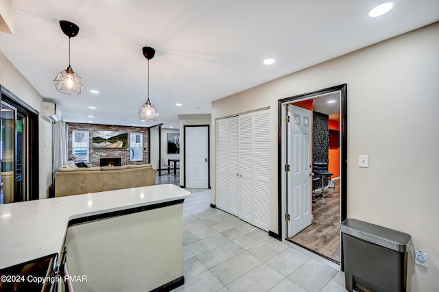 kitchen with light tile patterned floors, recessed lighting, a fireplace, an AC wall unit, and pendant lighting