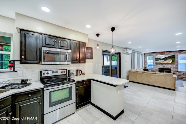 kitchen featuring a fireplace, light countertops, appliances with stainless steel finishes, decorative backsplash, and a wall mounted air conditioner