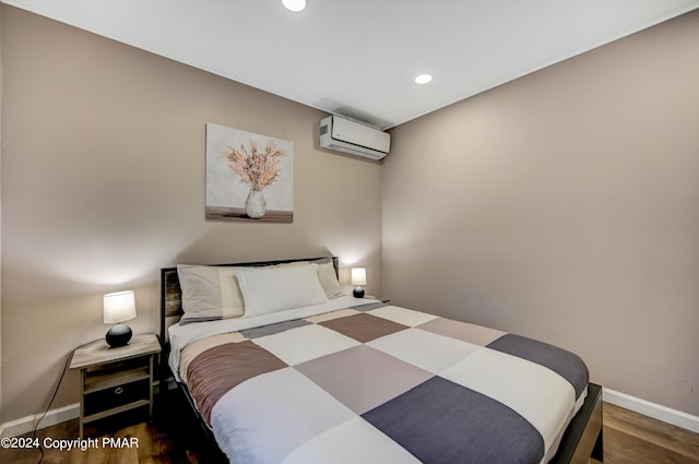 bedroom with a wall unit AC, baseboards, wood finished floors, and recessed lighting