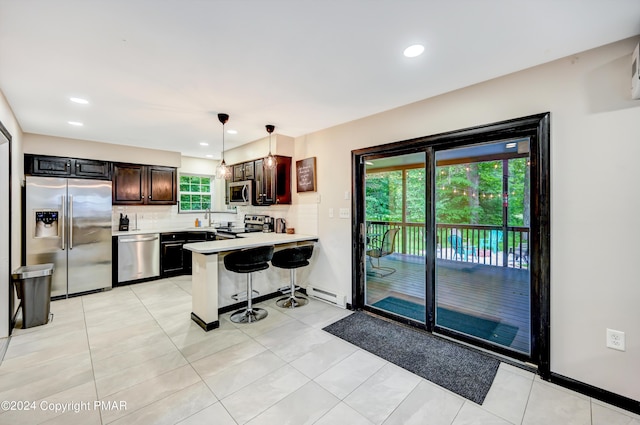 kitchen featuring stainless steel appliances, a peninsula, a kitchen breakfast bar, light countertops, and decorative backsplash